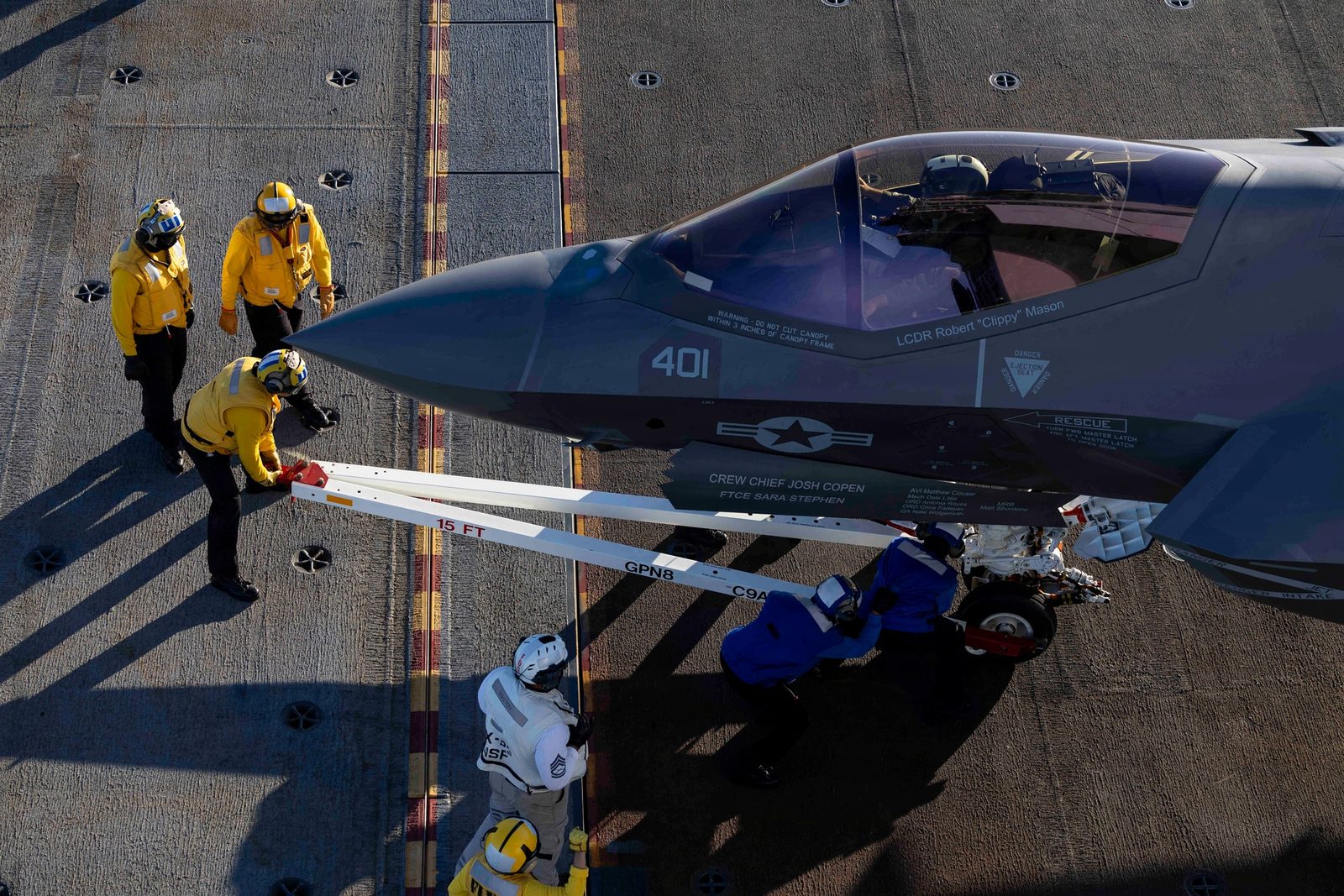 空母の飛行甲板で、甲板要員が米海軍のF-35Cにトウバーを取り付ける様子（2026年10月）